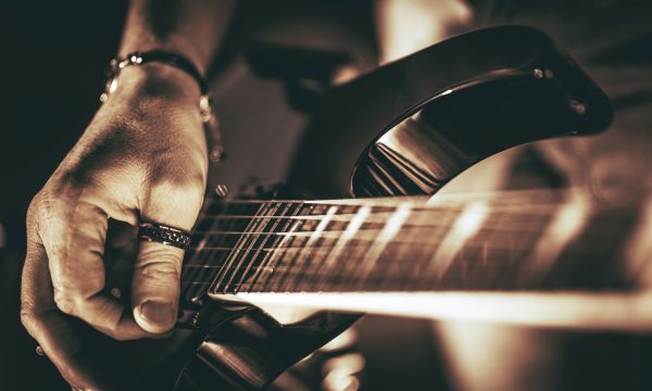 Rockman Guitar Player Guitarist Plays. Electric Guitar Playing Closeup Photo. Rockman Guitar Player Music Theme.